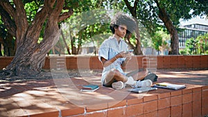 African girl messaging cellphone sitting city park. Teenager smiling reading sms