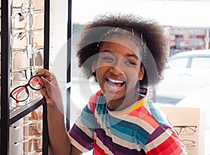 African girl in the optic store looking in the mirror for choosing a new eyeglasses frame. health care, medicine, people, eyesight