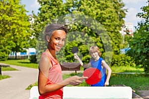 African girl playing ping pong with boy outside