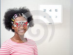 African girl putting optical trial frame to determine visual acuity. health care, medicine, people, eyesight and technology