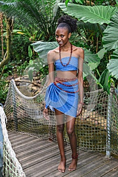 African girl stands on wooden bridge in jungle