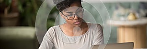 African girl wear glasses looking at pc screen studying online