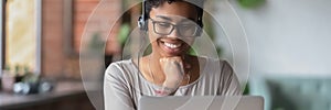 Smiling African girl wear headphones watch online webinar use laptop photo