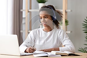 African girl wearing headphones study with skype teacher on laptop