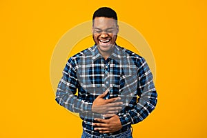 African Guy Laughing Out Loud Standing Over Yellow Background, Studio