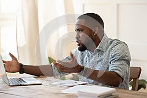 African guy looks at pc screen talking feels outraged