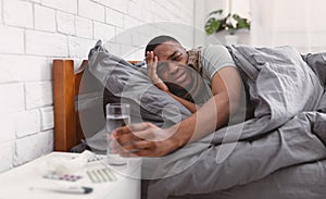 African Guy Taking Medication Having Fever Lying In Bed Indoor