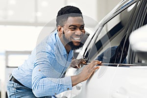 African Guy Touching His New Vehicle In Dealership Showroom