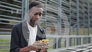 African guy using mobilephone outside.