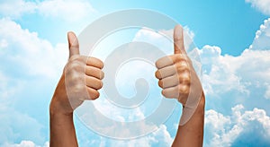 African hands showing thumbs up over blue sky