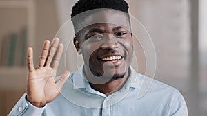 African handsome friendly man american young guy blogger teacher coach say hello look at camera wave hand greeting