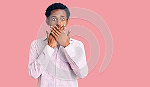 African handsome man wearing casual pink shirt shocked covering mouth with hands for mistake
