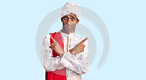 African handsome man wearing tradition sherwani saree clothes pointing to both sides with fingers, different direction disagree