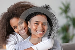 African happy mother and daughter cuddling looking at camera