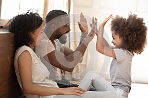 African kid daughter give high-five to daddy playing with parents