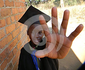 African kid in graduation attire showing open palm