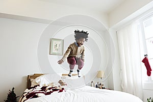African kid having a fun time jumping on a bed