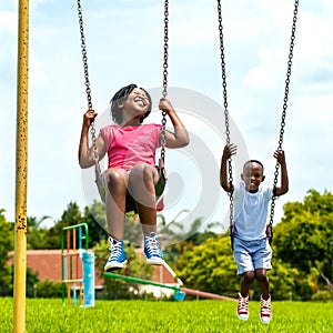 African kids having fun swinging in park.