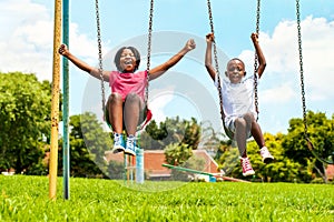 African kids playing on swing in neighborhood.