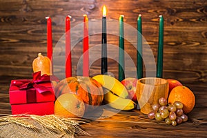 african Kwanzaa festive concept with decorative candles red, black and green, gift box, pumpkins, ears photo