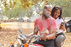 an african lady on a bike and the rider view content on phone