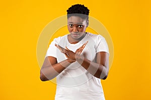 African Lady Crossing Hands Showing Forbidding Gesture, Yellow Background