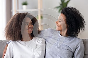 African loving mother embracing looking at adolescent daughter