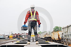African machine engineer technician wearing a helmet, groves and safety vest is using a wrench to repair the train