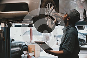 African maintenance male checking car, service via insurance system at automobile repair and check up center