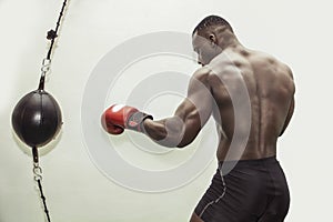 African male boxer punching ball wearing boxing gloves