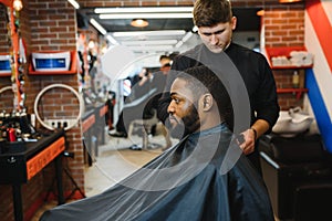 African male client getting haircut at barber shop from professional hairstylist