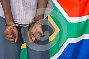 African male with handcuffs on the background of the South Africa flag