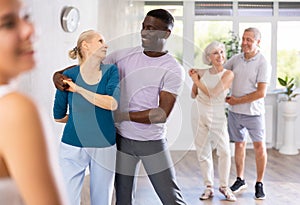 African male novice student of fitness studio practices paired Latin American rumba dance