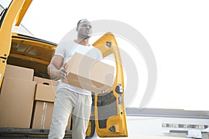 african male postal delivery courier man in front of car delivering package