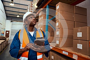 African male supervisor checking product or parcel goods on shelf pallet in industry storage warehouse using digital