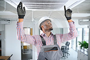 african Male Technician Repairing Air Conditioner.