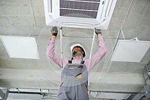 african Male Technician Repairing Air Conditioner.