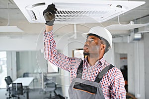 african Male Technician Repairing Air Conditioner.