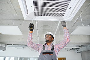 african Male Technician Repairing Air Conditioner.