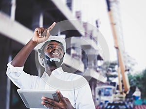 African man architect at building site. African American Engineer man use tablet device standing communication at construction