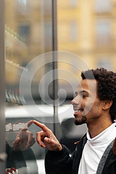 African man buys drink or sweets at vending machine outside