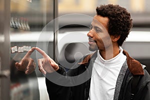 African man buys drink or sweets at vending machine outside