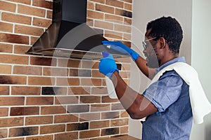 African man cleaning cooktop cooker hood at home ,Brick wall background