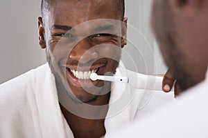 African Man Cleaning His Teeth In Front Of Mirror