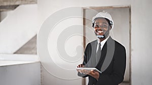 African man construction engineer manager using tablet and looking the unfinished building