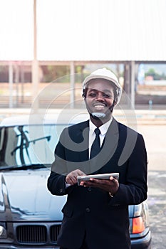 African man construction engineer worker standing and use teblet with the car