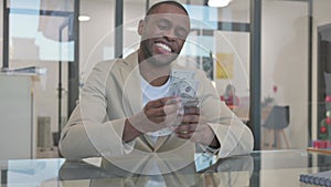 African Man Counting Money in Office