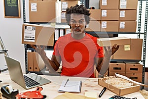 African man with curly hair working at small business ecommerce looking at the camera blowing a kiss being lovely and sexy