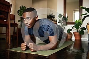 African man doing the forearm plank during a yoga at home