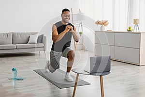 African Man Doing Forward Lunge Exercise Watching Online Workout Indoor photo
